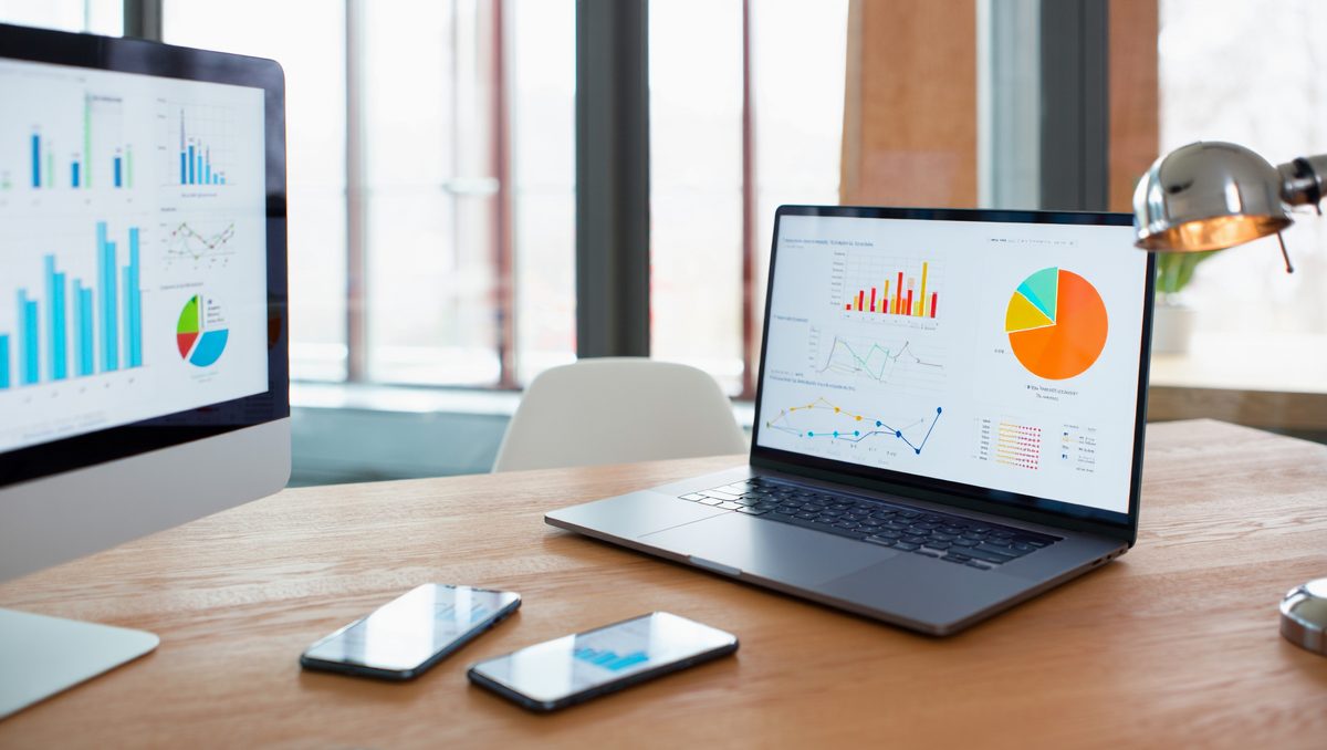 Laptop and monitor displaying bar charts and a pie chart