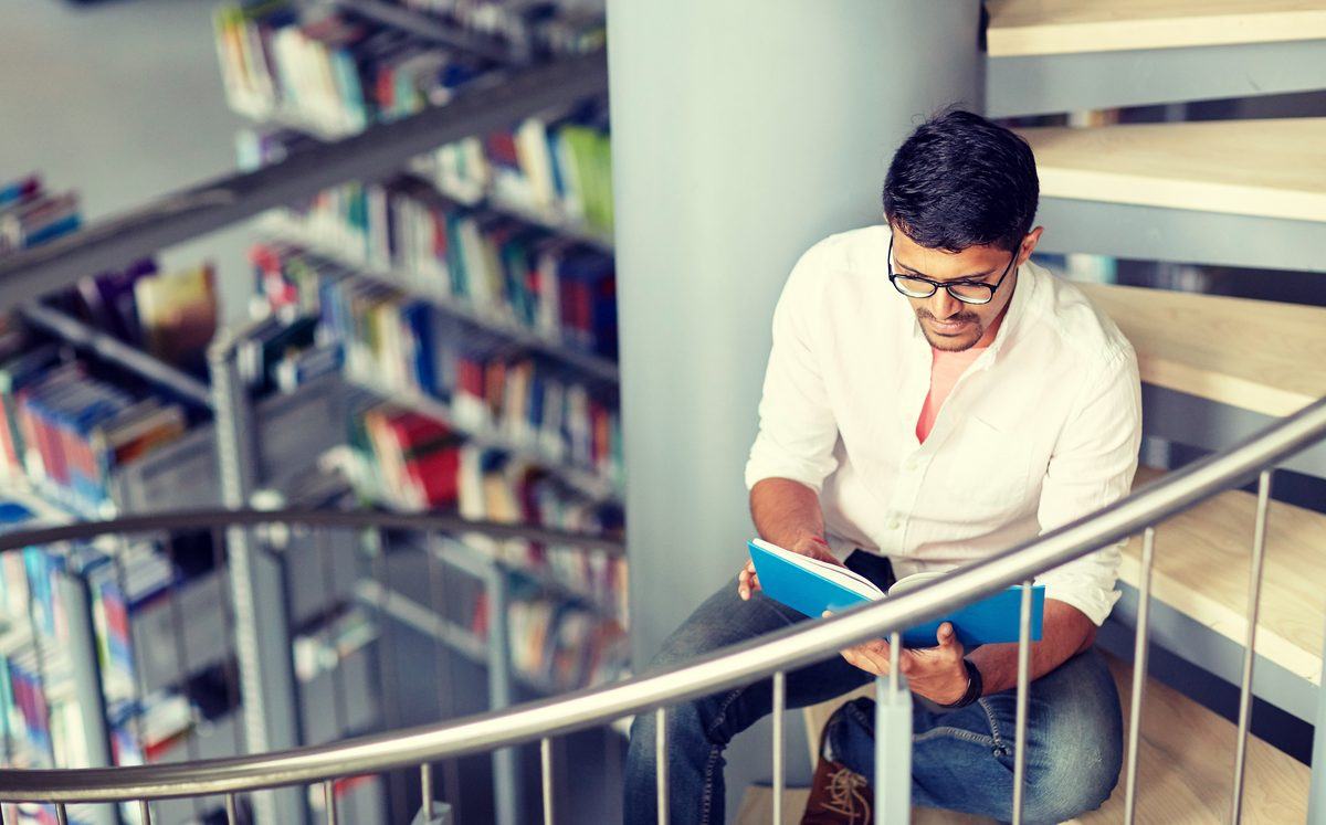 Student reading on the stairs of a university library